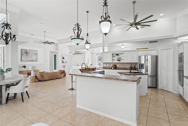 kitchen with pendant lighting, ceiling fan, appliances with stainless steel finishes, white cabinets, and decorative backsplash