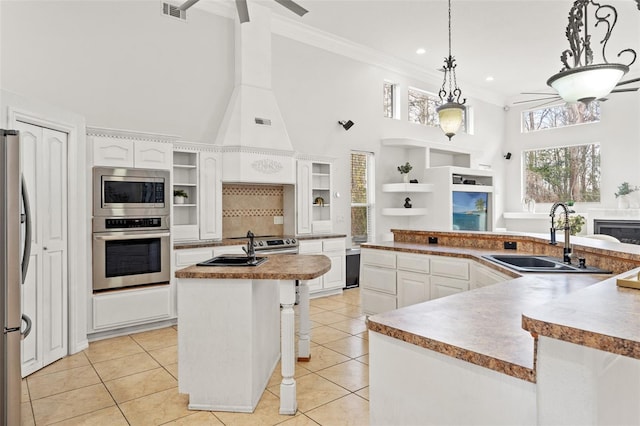 kitchen with sink, appliances with stainless steel finishes, a kitchen island with sink, white cabinetry, and decorative light fixtures