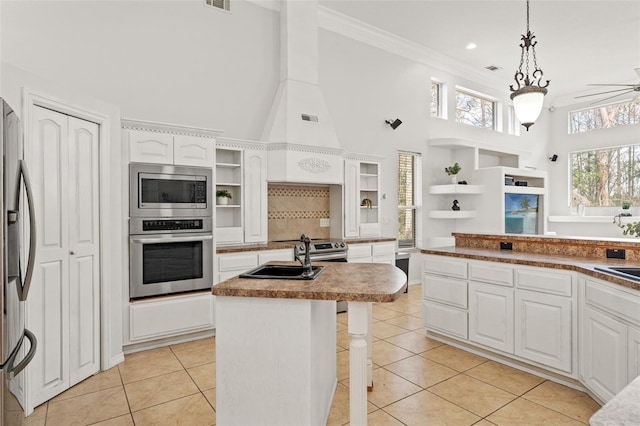 kitchen with white cabinetry, stainless steel appliances, a center island, and light tile patterned flooring