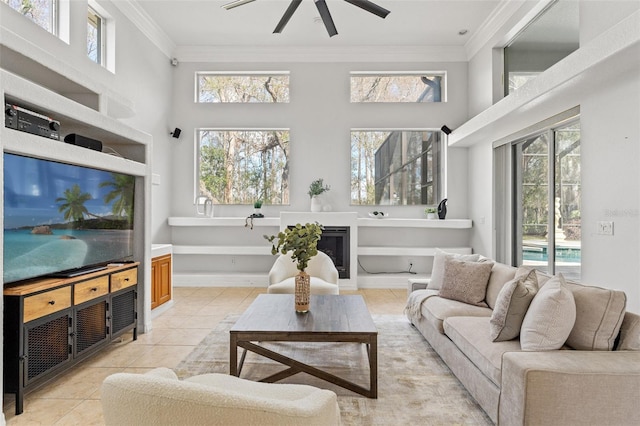 living room featuring a high ceiling, ornamental molding, ceiling fan, and light tile patterned flooring