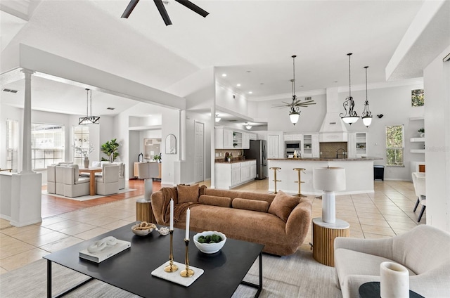 tiled living room with ceiling fan, a healthy amount of sunlight, sink, and decorative columns