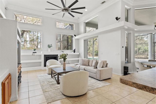 living room with light tile patterned floors, a towering ceiling, ornamental molding, and ceiling fan