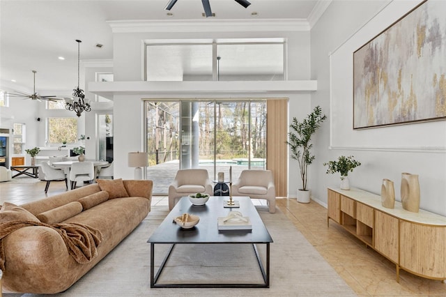 living room featuring ceiling fan with notable chandelier, a fireplace, and ornamental molding