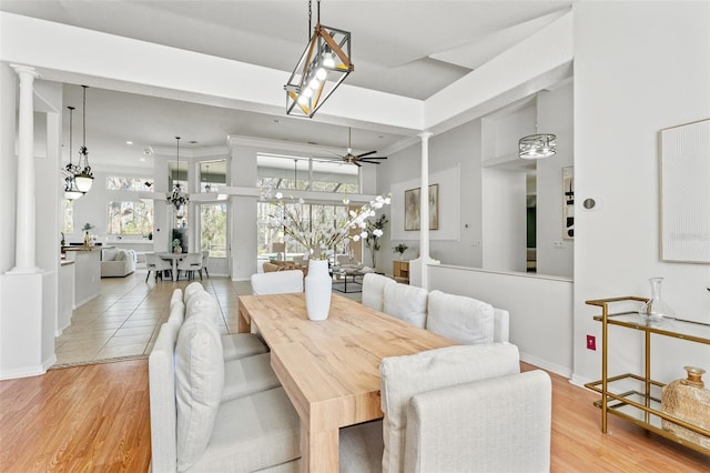 dining area with ornate columns, ceiling fan, crown molding, and light wood-type flooring