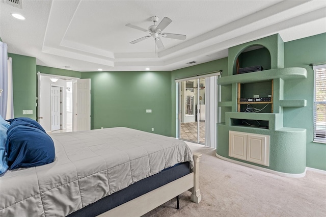 carpeted bedroom featuring a raised ceiling and ceiling fan