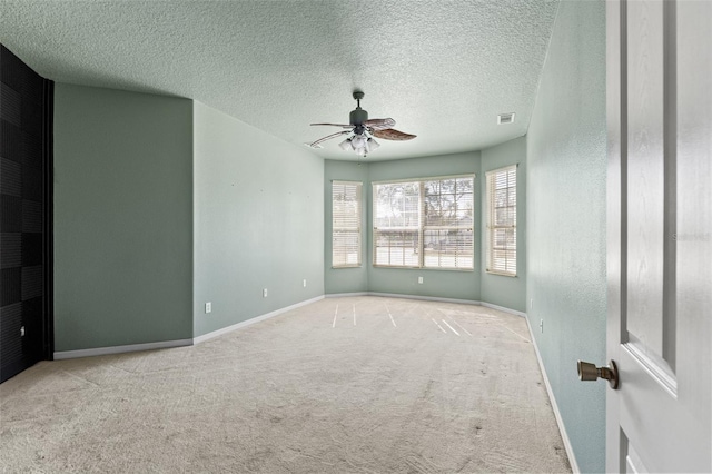 spare room featuring ceiling fan, light carpet, and a textured ceiling