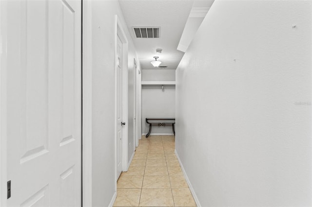 hallway featuring light tile patterned flooring and a textured ceiling