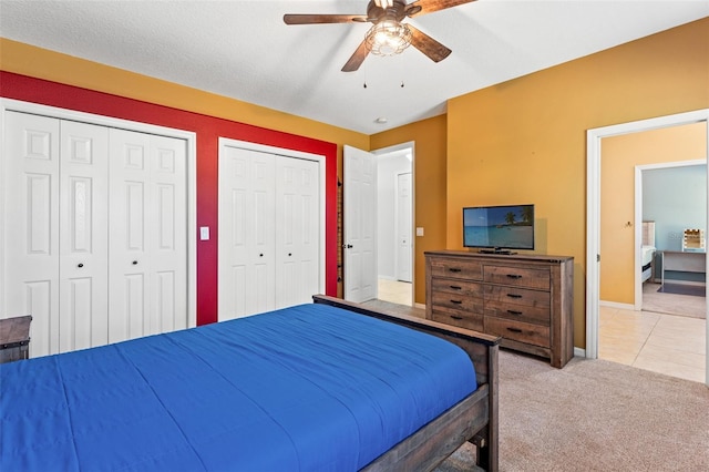 carpeted bedroom with multiple closets and ceiling fan