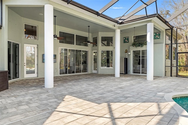 rear view of property with glass enclosure, ceiling fan, and a patio area