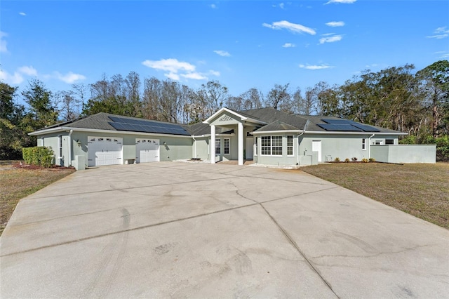 single story home with a garage, a front lawn, and solar panels