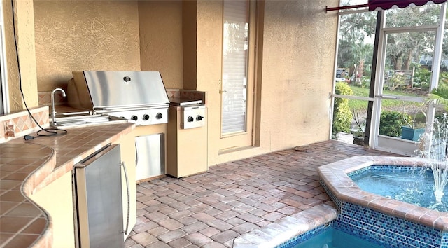 exterior space with brick floor, freestanding refrigerator, a textured wall, and tile countertops