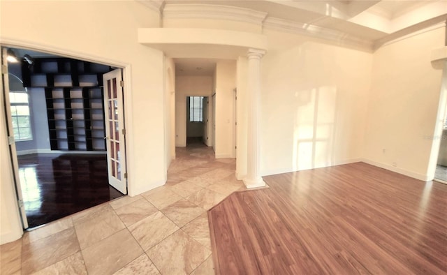 unfurnished room with light wood-style floors, baseboards, crown molding, and ornate columns