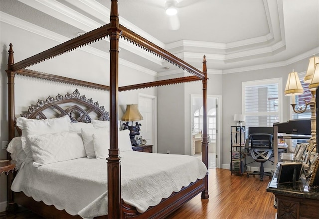 bedroom featuring ornamental molding, a raised ceiling, connected bathroom, and wood finished floors