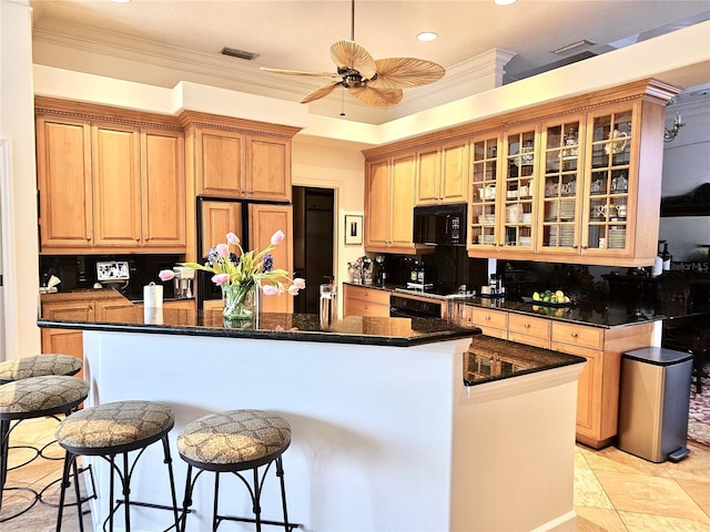 kitchen featuring tasteful backsplash, visible vents, a kitchen island, glass insert cabinets, and black microwave