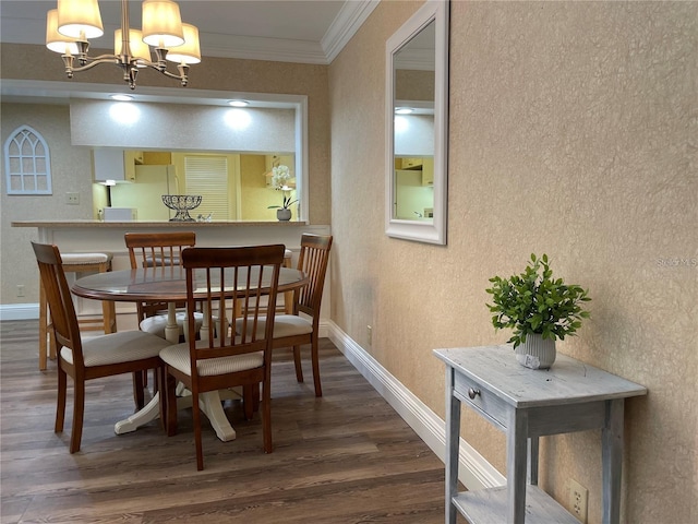 dining room featuring dark wood-type flooring, ornamental molding, and an inviting chandelier