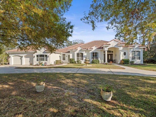 mediterranean / spanish home featuring a garage and a front lawn