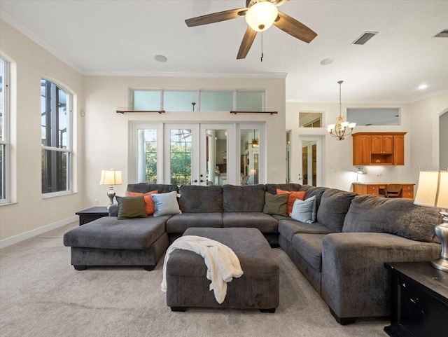 carpeted living room with crown molding, ceiling fan with notable chandelier, and french doors