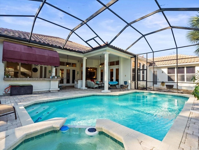 view of swimming pool featuring french doors, a patio area, glass enclosure, an outdoor bar, and ceiling fan