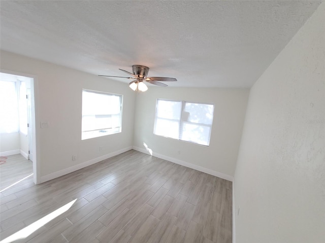 spare room featuring ceiling fan, light hardwood / wood-style flooring, and a textured ceiling