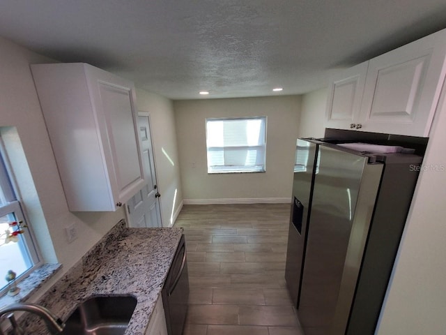 kitchen with sink, white cabinetry, light stone counters, and stainless steel refrigerator with ice dispenser