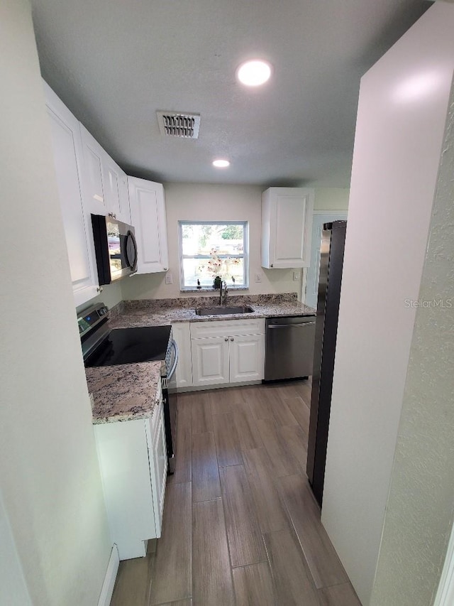 kitchen with light hardwood / wood-style flooring, sink, stainless steel appliances, white cabinets, and light stone countertops