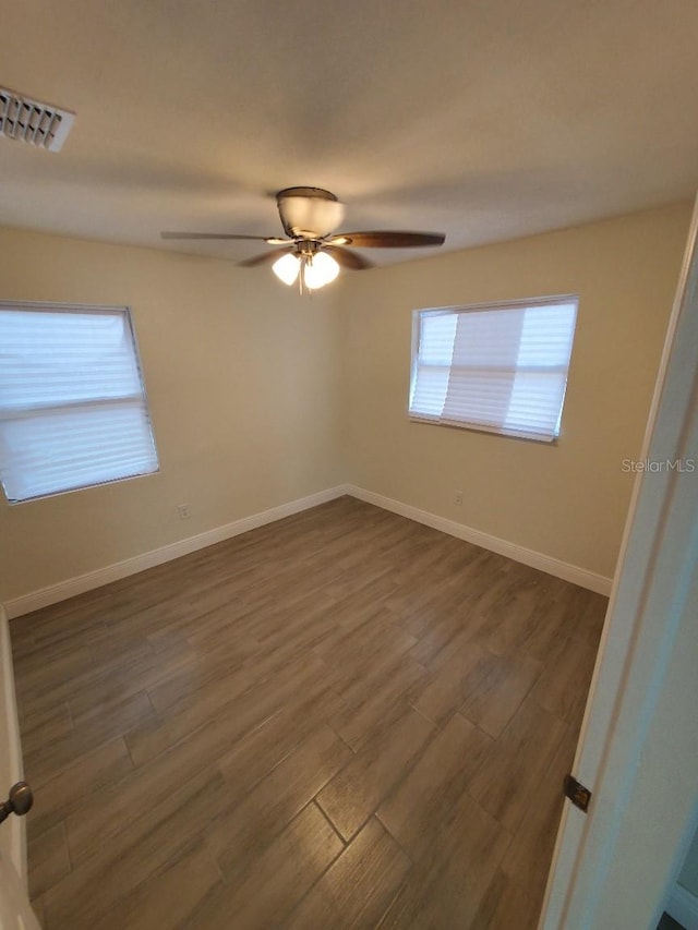 empty room with dark hardwood / wood-style flooring and ceiling fan