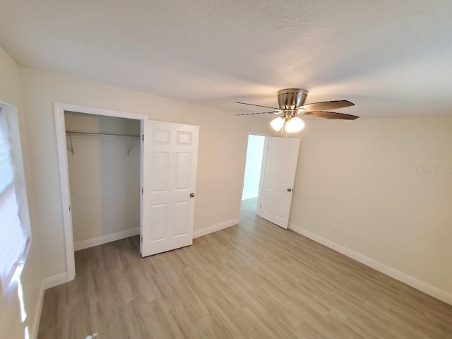 unfurnished bedroom featuring ceiling fan, light wood-type flooring, a textured ceiling, and a closet