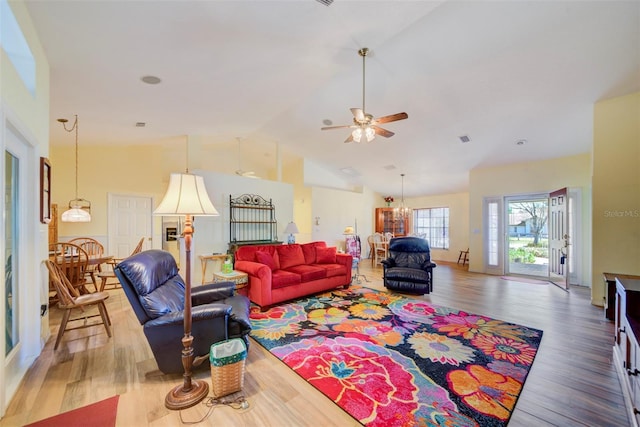 living room with ceiling fan with notable chandelier, high vaulted ceiling, and hardwood / wood-style floors