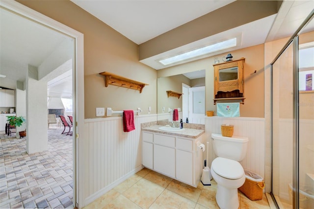 bathroom with walk in shower, toilet, a skylight, vanity, and tile patterned flooring