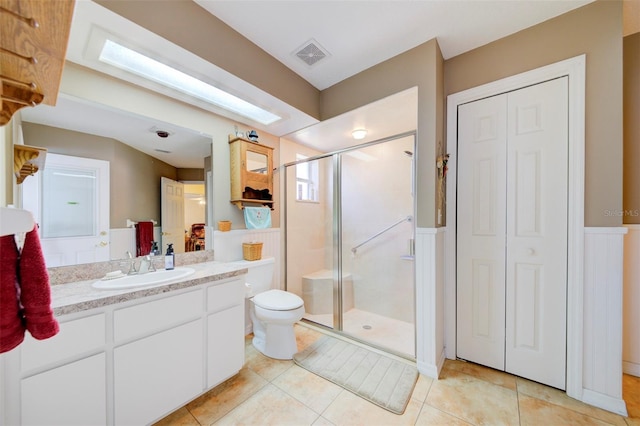 bathroom featuring vanity, tile patterned floors, toilet, and walk in shower