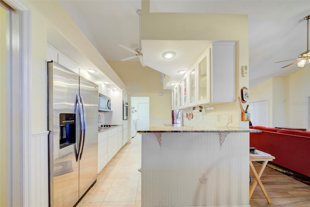 kitchen with a breakfast bar, kitchen peninsula, ceiling fan, stainless steel appliances, and white cabinets