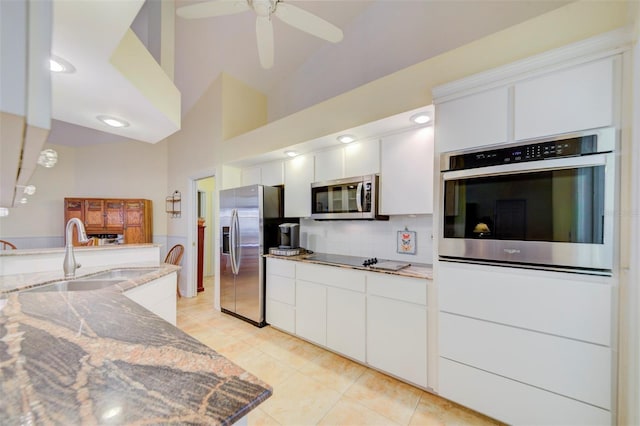 kitchen with appliances with stainless steel finishes, tasteful backsplash, sink, white cabinets, and light stone counters