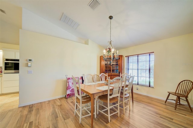 dining room featuring lofted ceiling, light hardwood / wood-style flooring, and a notable chandelier