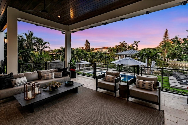 patio terrace at dusk with an outdoor living space and a balcony