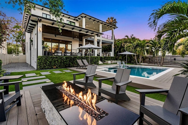 exterior space with fence, a fire pit, a wooden deck, and a fenced in pool