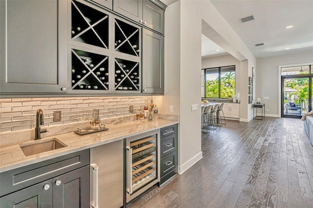 bar with indoor wet bar, tasteful backsplash, a sink, beverage cooler, and baseboards