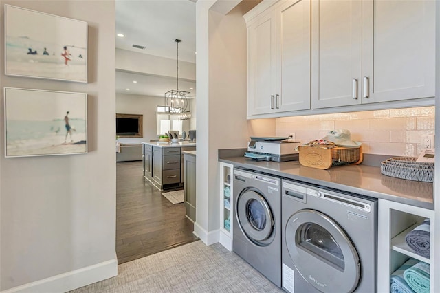 laundry area featuring cabinet space, independent washer and dryer, an inviting chandelier, and baseboards