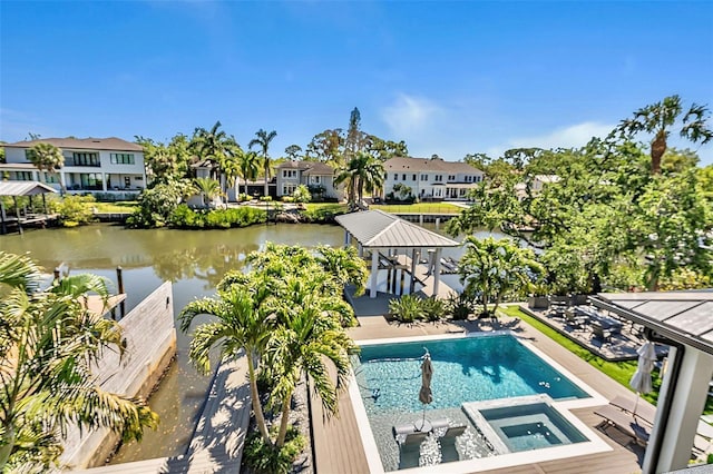 pool with a water view, a residential view, and an in ground hot tub