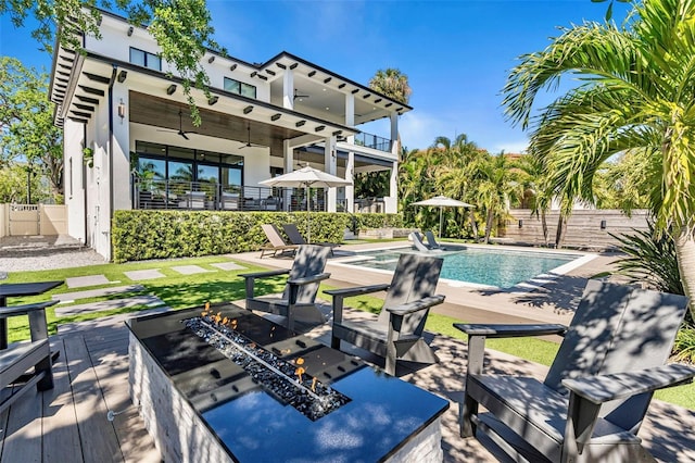 exterior space featuring a fire pit, ceiling fan, fence, a patio, and a fenced in pool