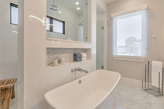 bathroom featuring a tile shower, marble finish floor, baseboards, and a wealth of natural light