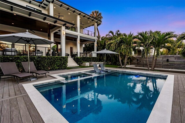 5004 S The Riviera, Tampa, FL 33609 - pool at dusk featuring a ceiling fan, a pool with connected hot tub, stairs, and a patio