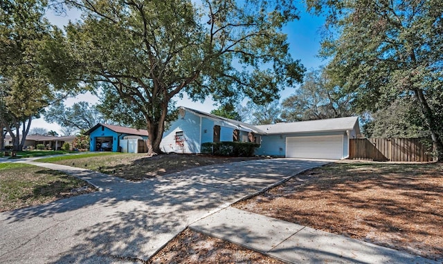 view of front of house featuring concrete driveway, an attached garage, and fence