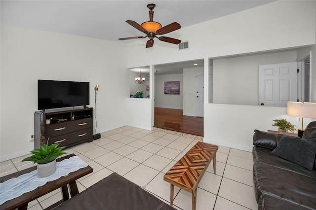 tiled living room featuring vaulted ceiling and ceiling fan with notable chandelier