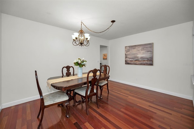 dining area with dark wood-type flooring and a chandelier