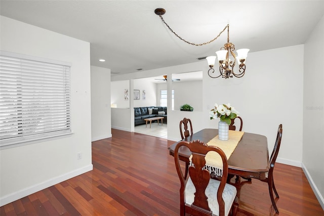 dining area with hardwood / wood-style flooring and ceiling fan with notable chandelier