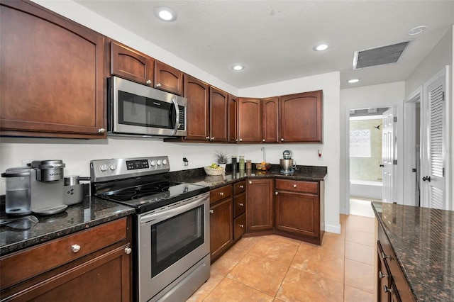 kitchen with dark stone countertops, light tile patterned floors, and appliances with stainless steel finishes