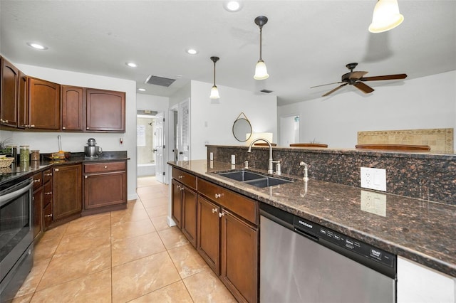 kitchen with sink, hanging light fixtures, light tile patterned floors, dark stone counters, and stainless steel appliances