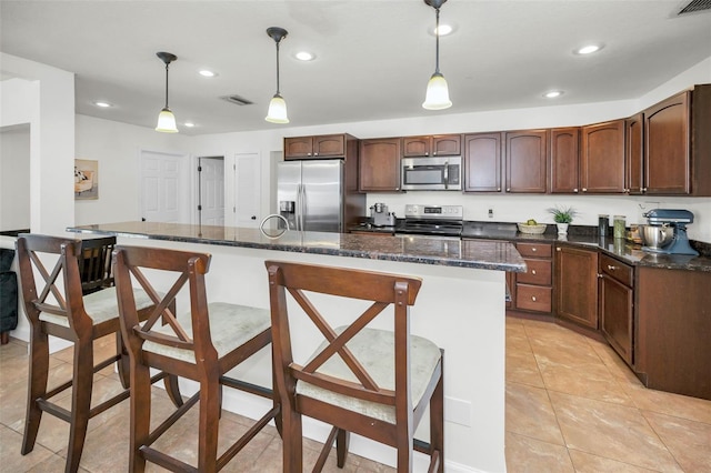 kitchen featuring hanging light fixtures, a kitchen island, a kitchen breakfast bar, and appliances with stainless steel finishes