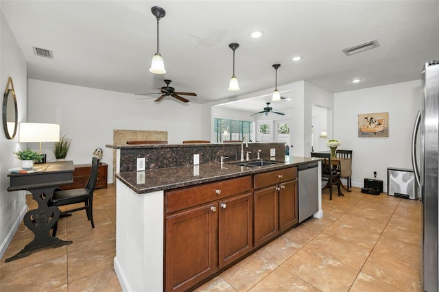 kitchen featuring sink, decorative light fixtures, appliances with stainless steel finishes, ceiling fan, and dark stone counters