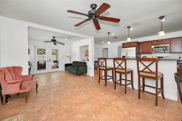 kitchen with a breakfast bar area, hanging light fixtures, light tile patterned floors, stainless steel appliances, and french doors